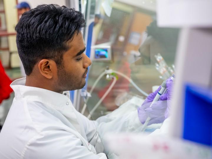 A student in lab coat uses pipette